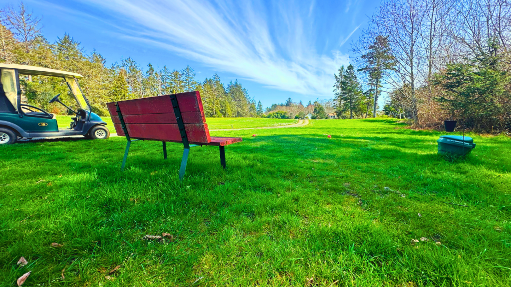 Bench on golf course with golf cart next to it