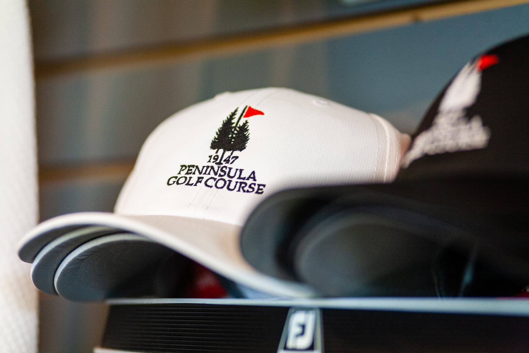Close-up of Peninsula Golf Course branded hat on display inside the pro shop, perfect for golfers and visitors